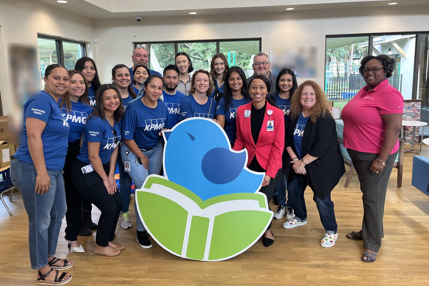 Community volunteers gathered around a large West Lakes Early Learning Center logo standee